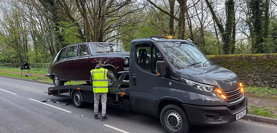 Classic saloon car being loaded onto a recovery truck